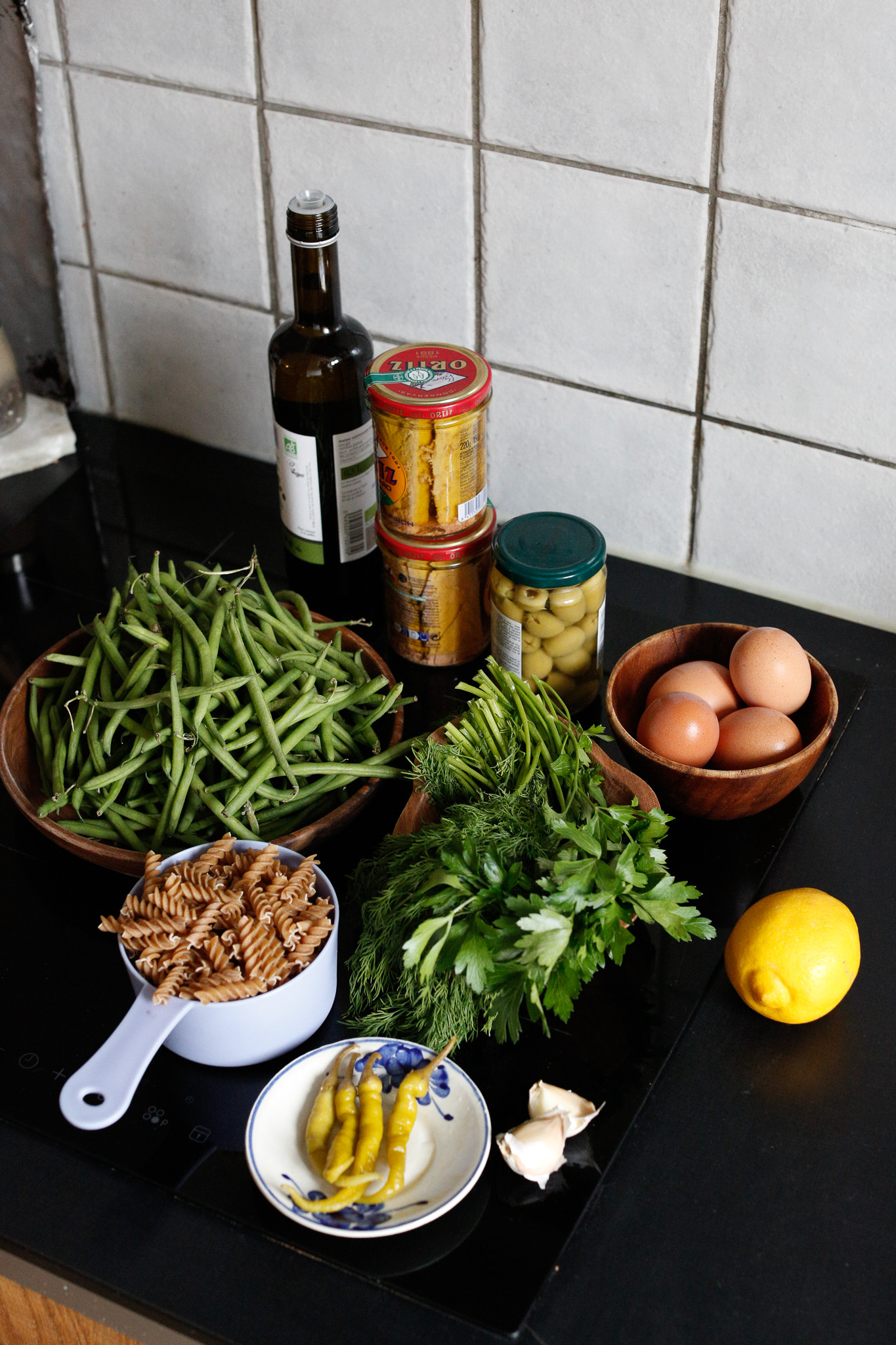 Gather ingredients. Eggs, spiral pasta, green beans, garlic, green olives, peppers, dill, parsley, olive oil, fresh lemon and good quality tuna in olive oil.