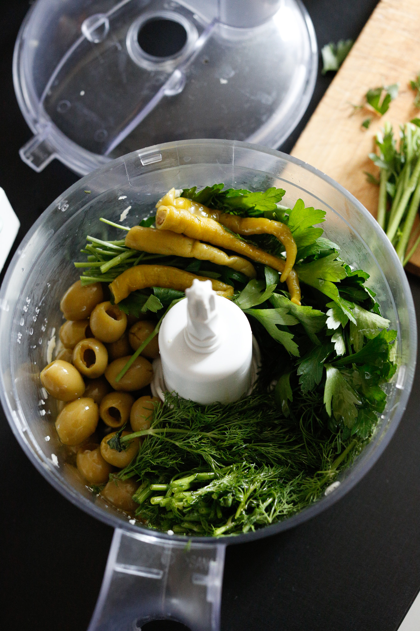 Add in your dill, parsley, pitted olives, peppers, olive oil, 1/2 lemon juice to start.