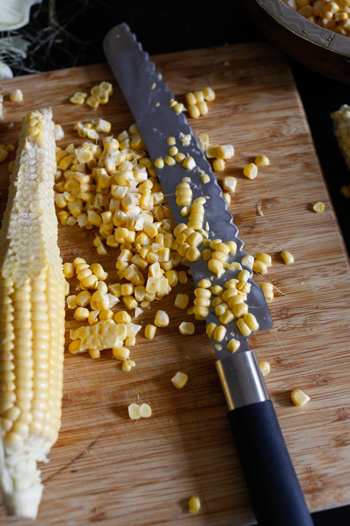 Hold your cob perpendicular to the cutting service and use a serated to gently cut downwards. To prevent your kernals from bouncing all over the place I do half a kern at a time. You can even break it in half if you prefer.