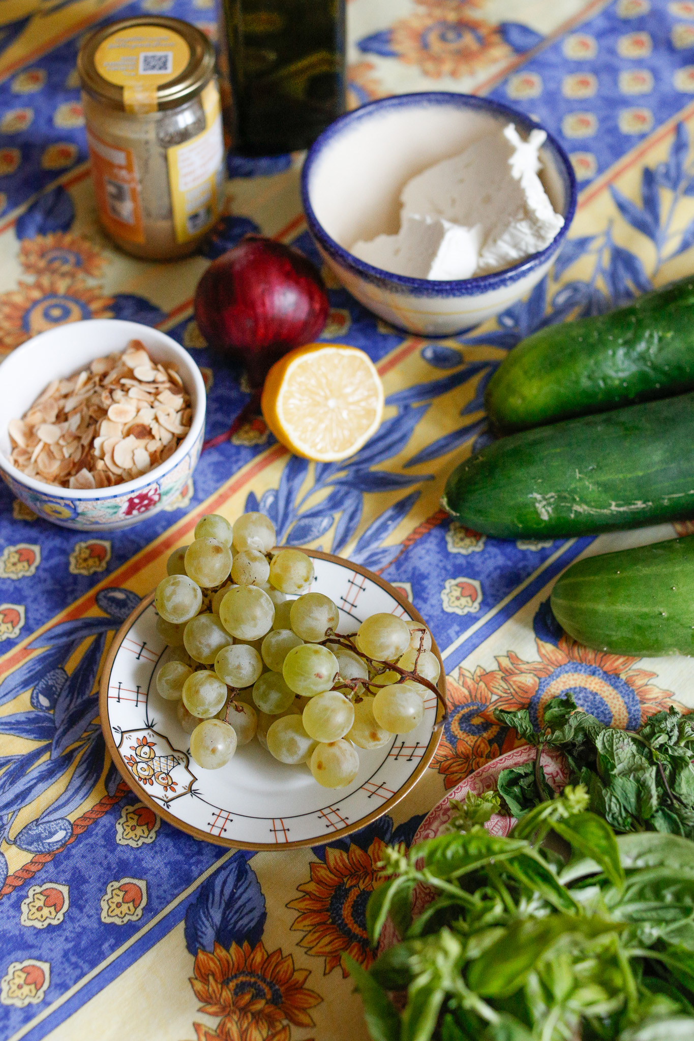 Gather all your ingredients. Cucumbers, grapes, red onion, almonds, herbs and salt. And for the dressing, tahini, fresh lemon, olive oil, salt and warm water.
