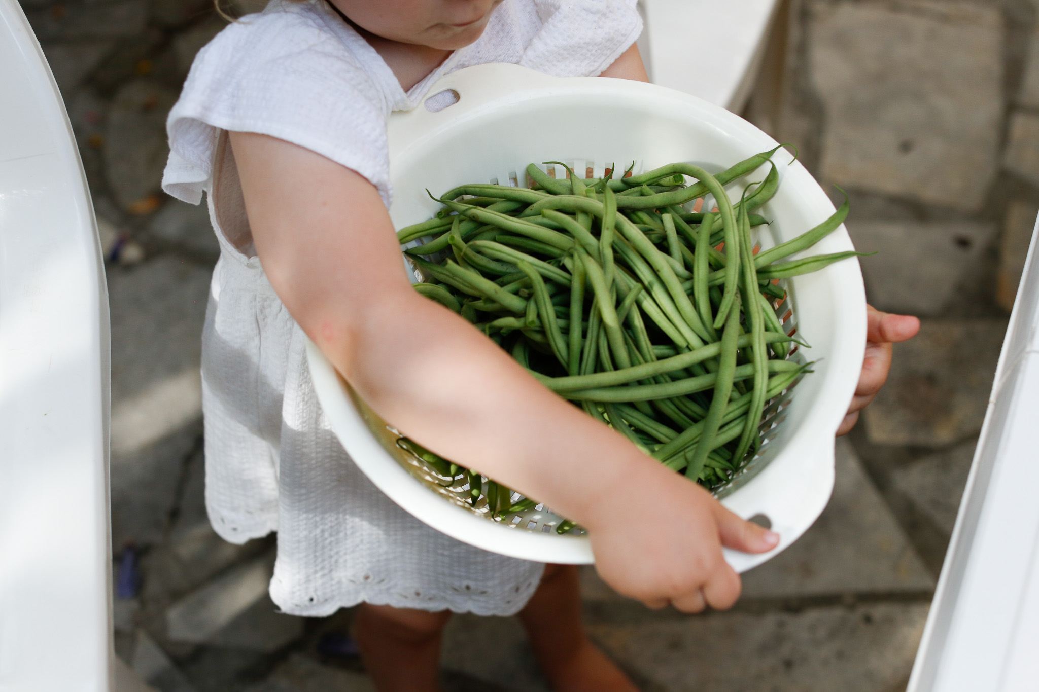 Child holding colander full of green beans