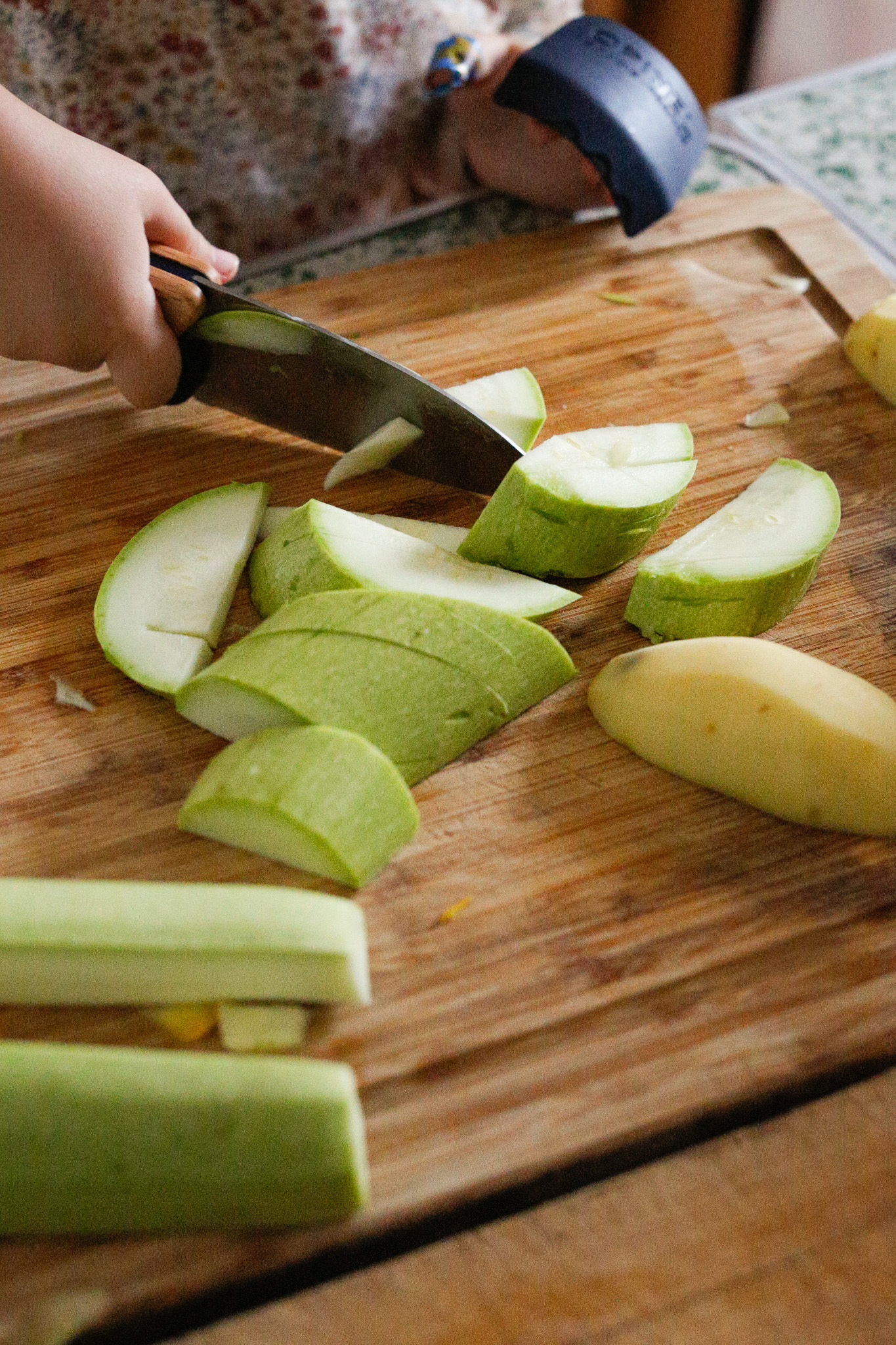 Kid cutting up squash in the kitchen