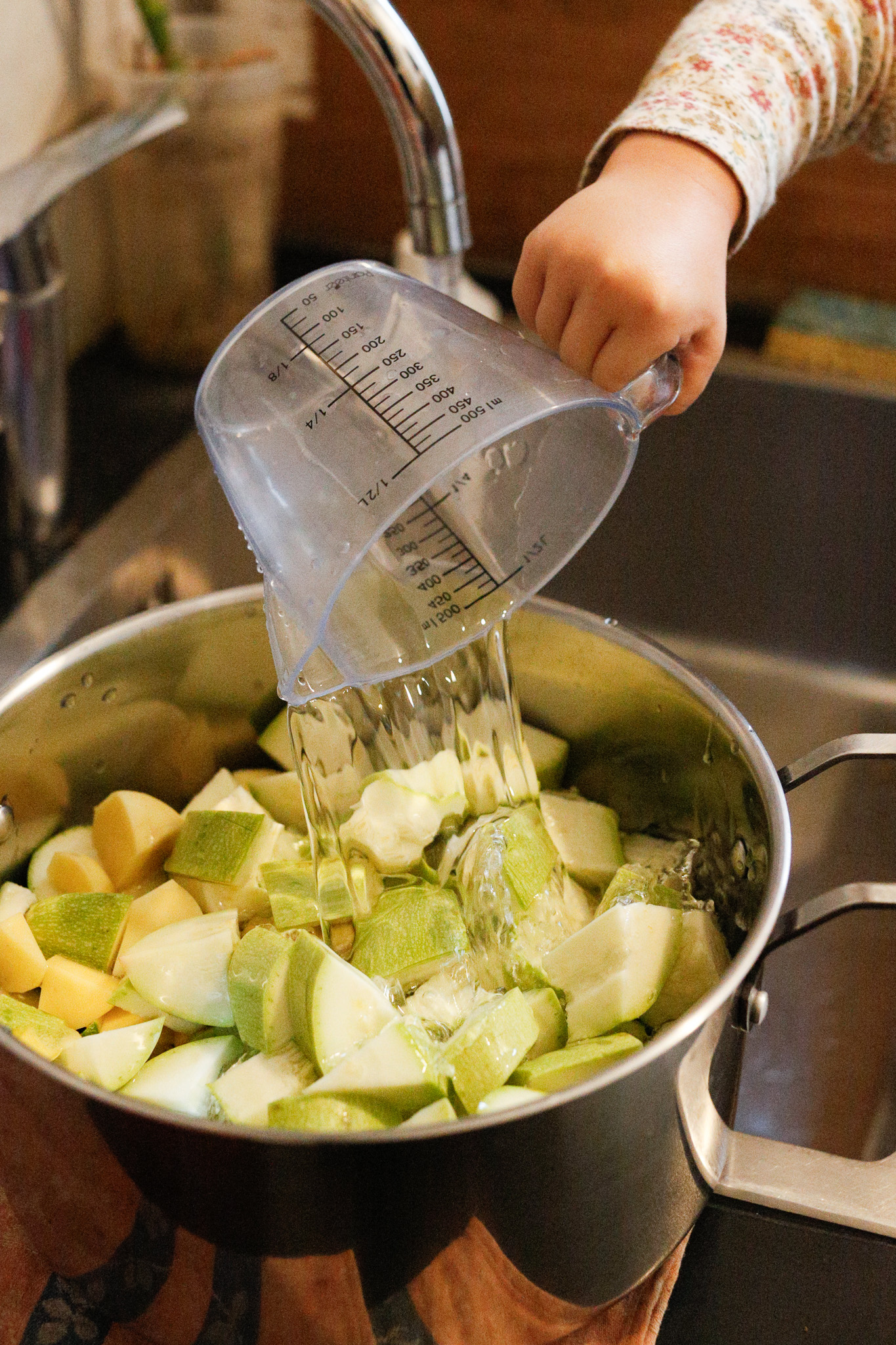 Using a pitcher or something with a handle, have them pour water into the pot to fill it up to just cover the contenents.