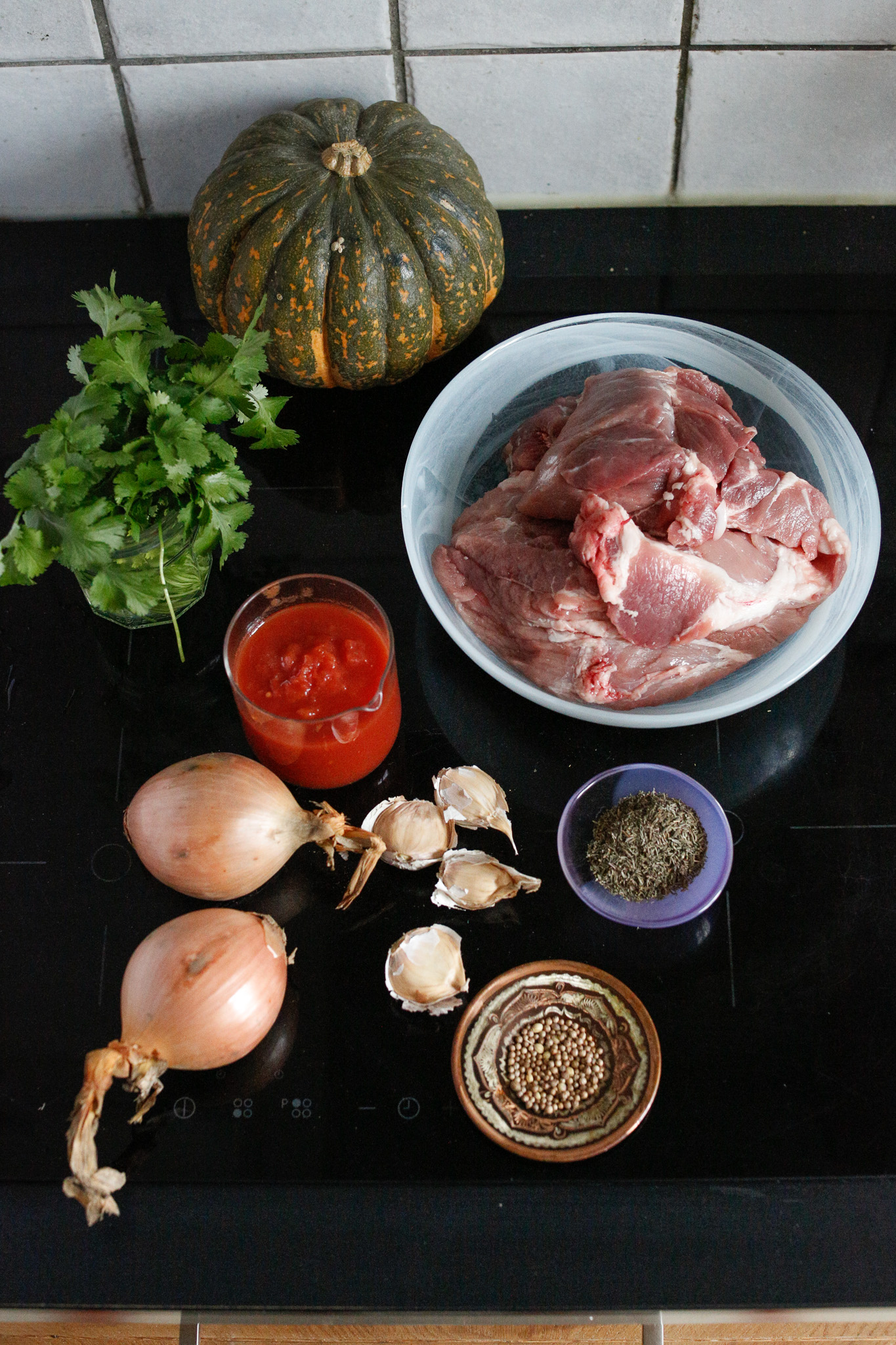 Gather your ingredients. Pork shoulder, herbs, coriander seeds, garlic, onions, tomatoe puree, kabocha squash, cilantro.