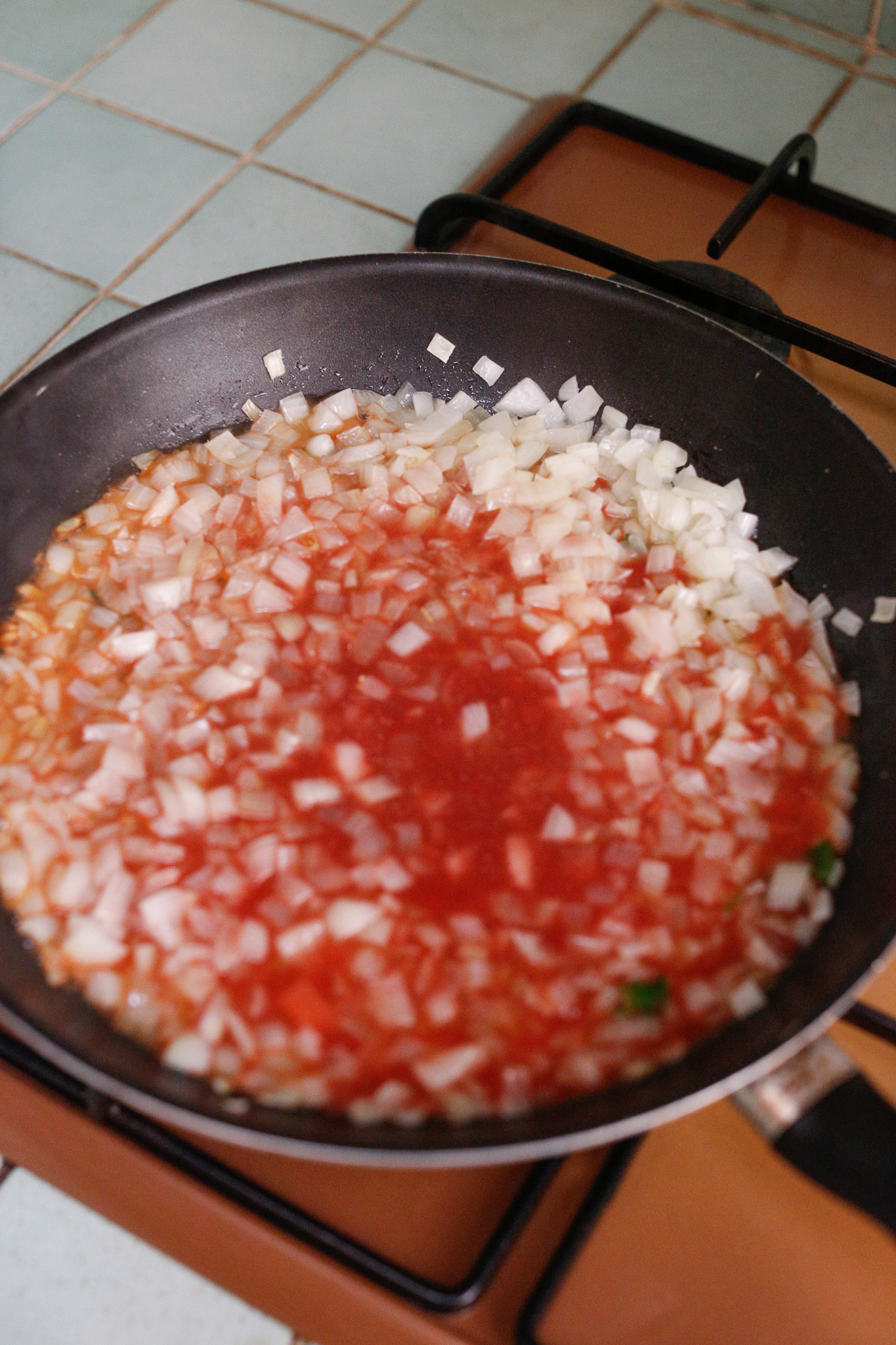 After a few minutes of softening your onions go ahead and in the tomato liquid. If you skipped this step, allow your onions to keep softening. You don't want them to brown much.