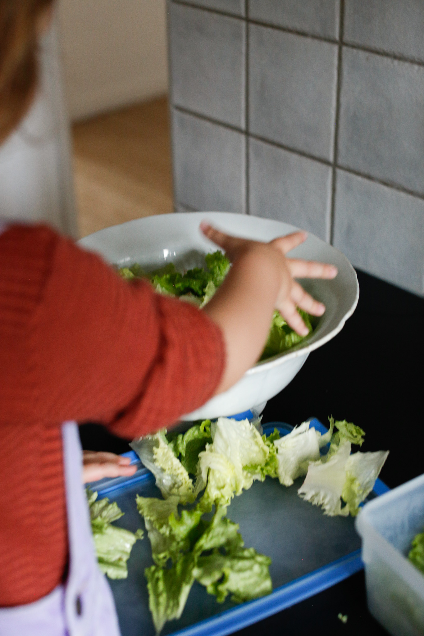 She puts the salad in the salad bowl at her own pace.